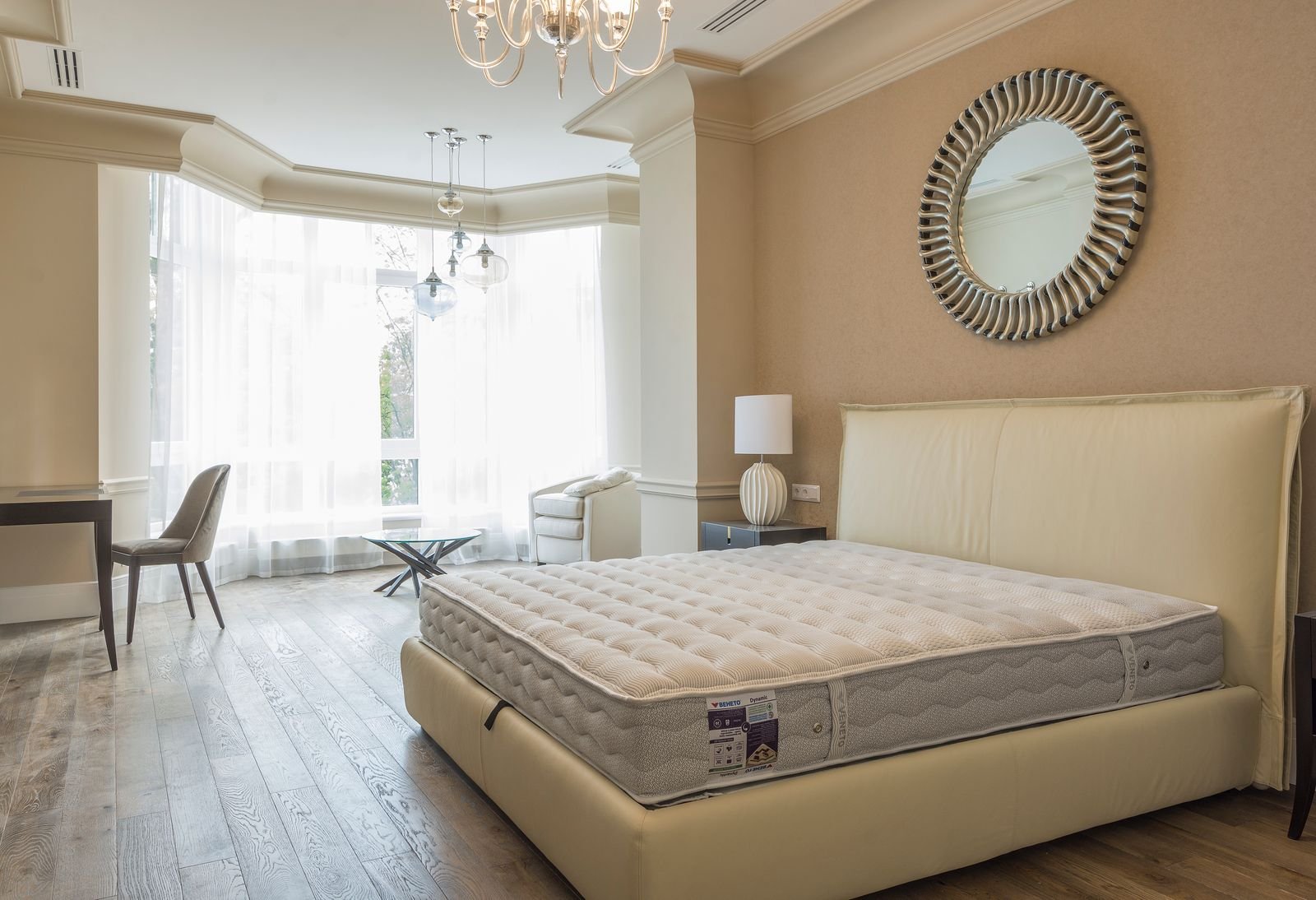 Bare mattress on a bed frame in a bright bedroom with a large window