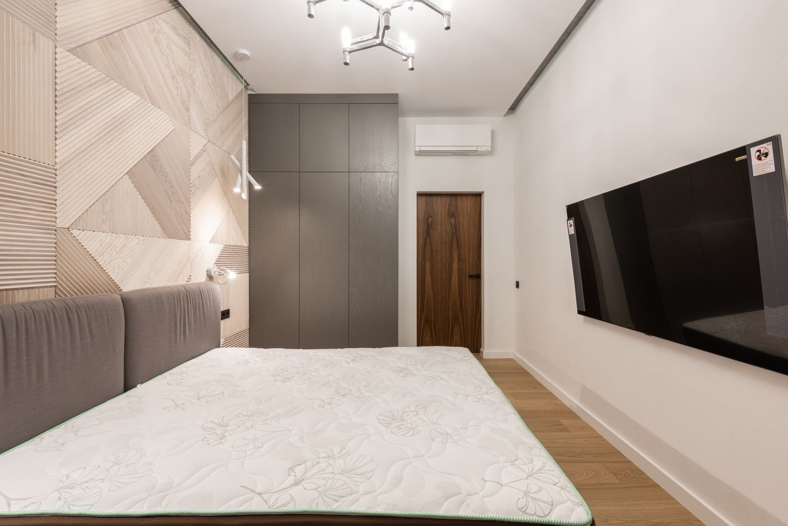 Bare mattress on a bed in a bedroom with a panelled feature wall