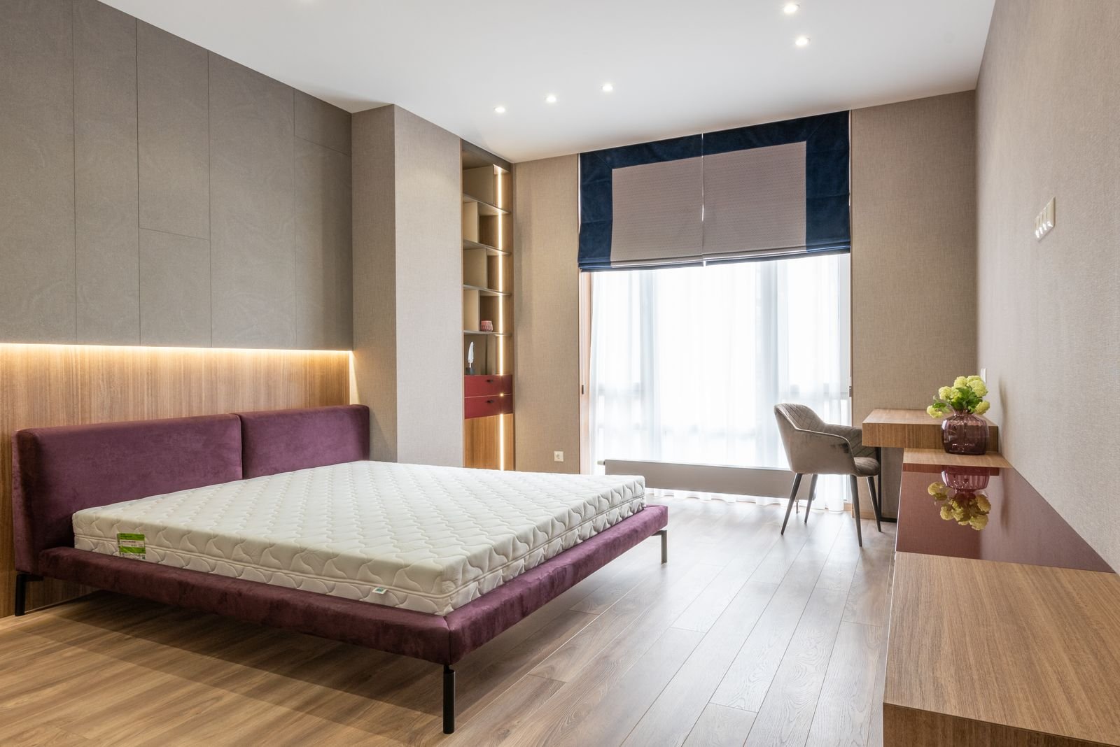 Bedroom with a bare mattress, purple cushions and a window seat