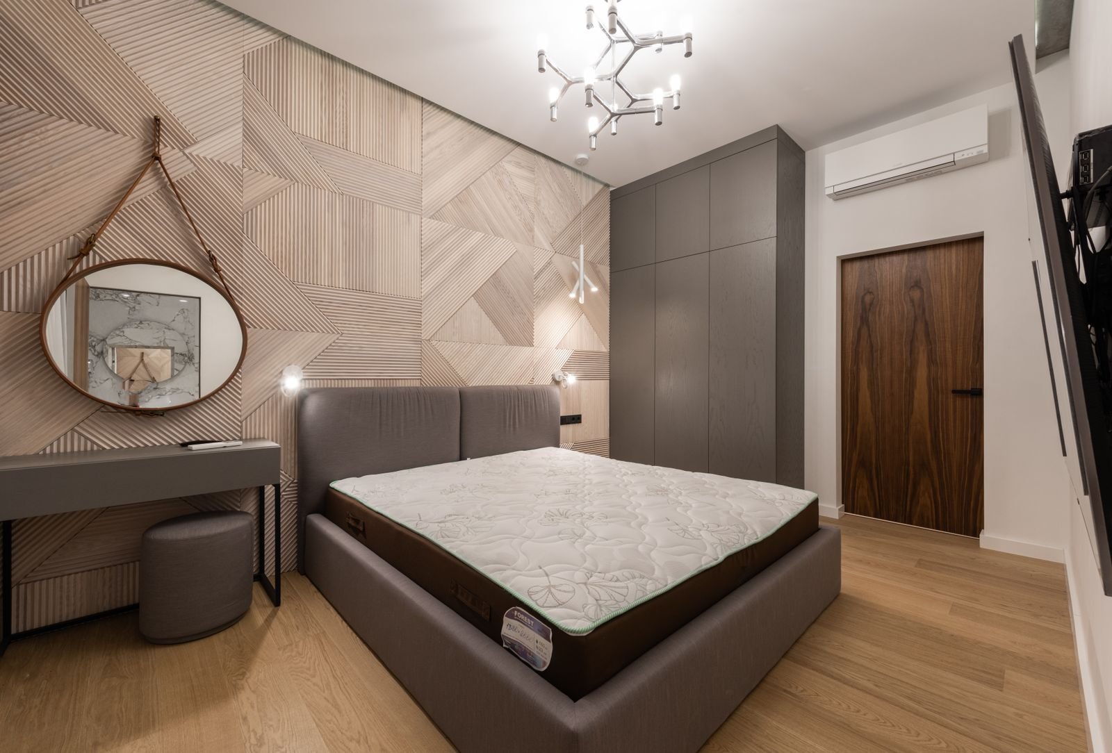 Bedroom with a bare mattress, round mirror and wood panelled wall