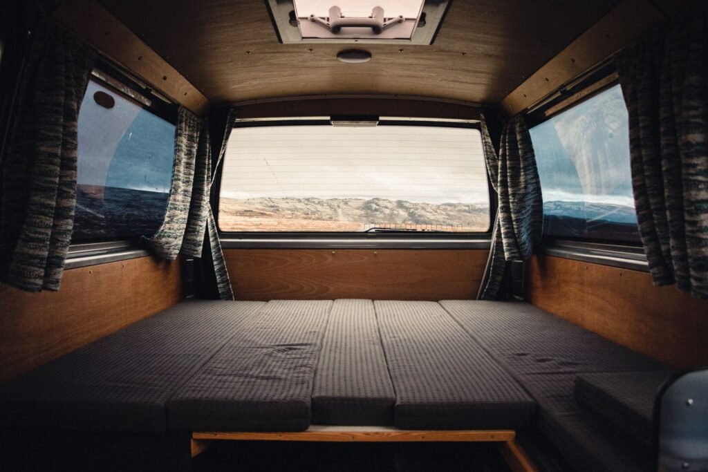 Interior of a campervan looking towards the rear window, showing the flat sleeping platform