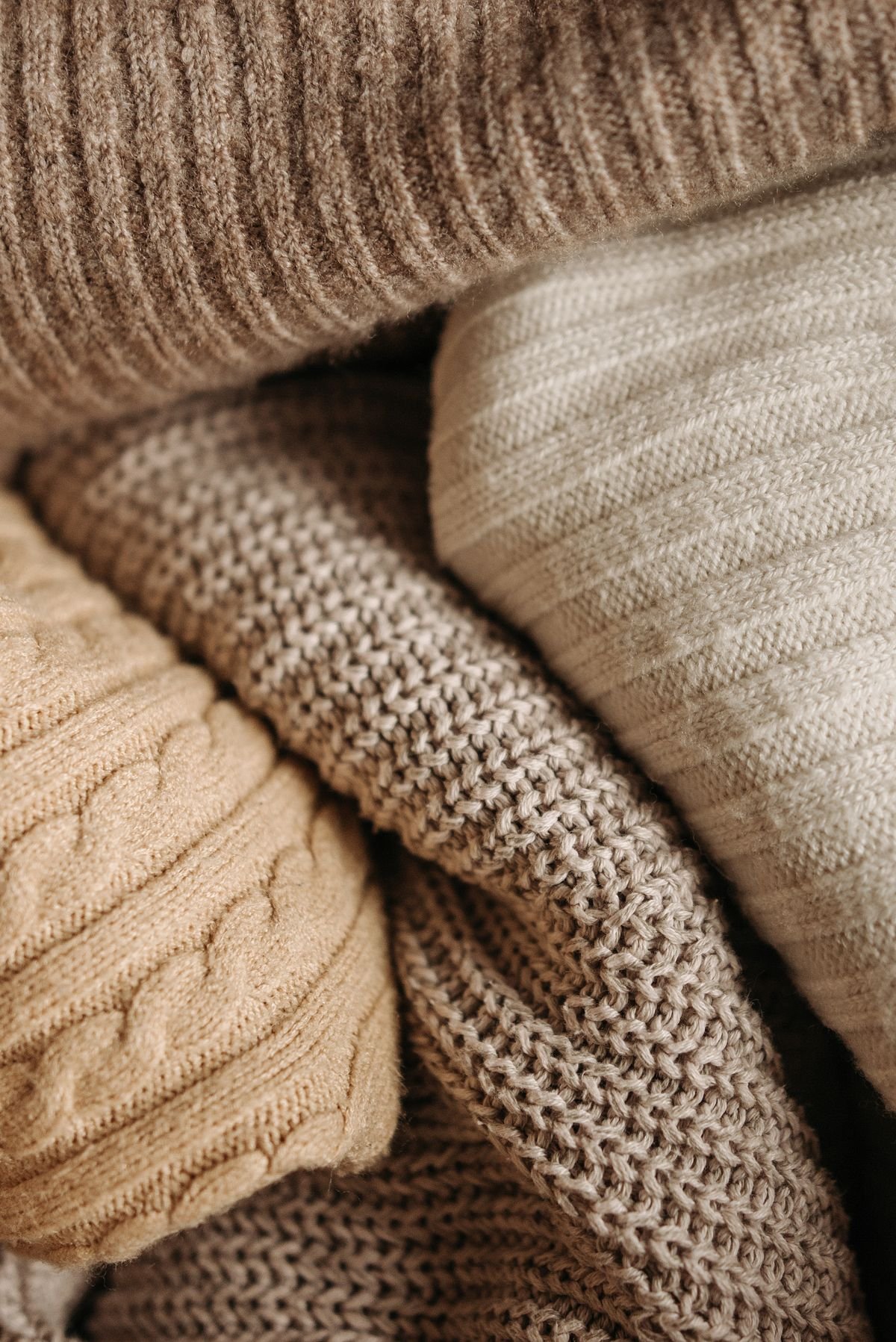 Chunky cream knitted blanket folded across a bed