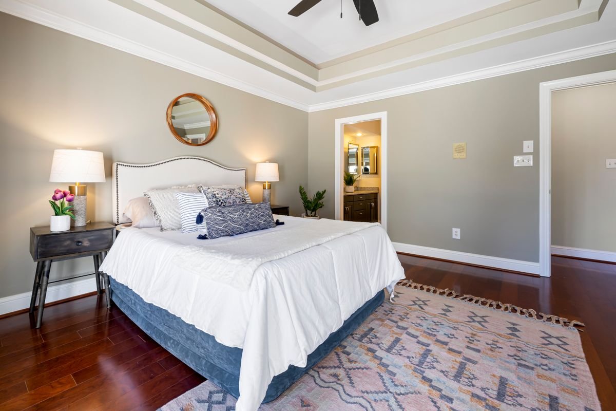 Classic bedroom with a white bed, dark wood furniture and a wall mirror