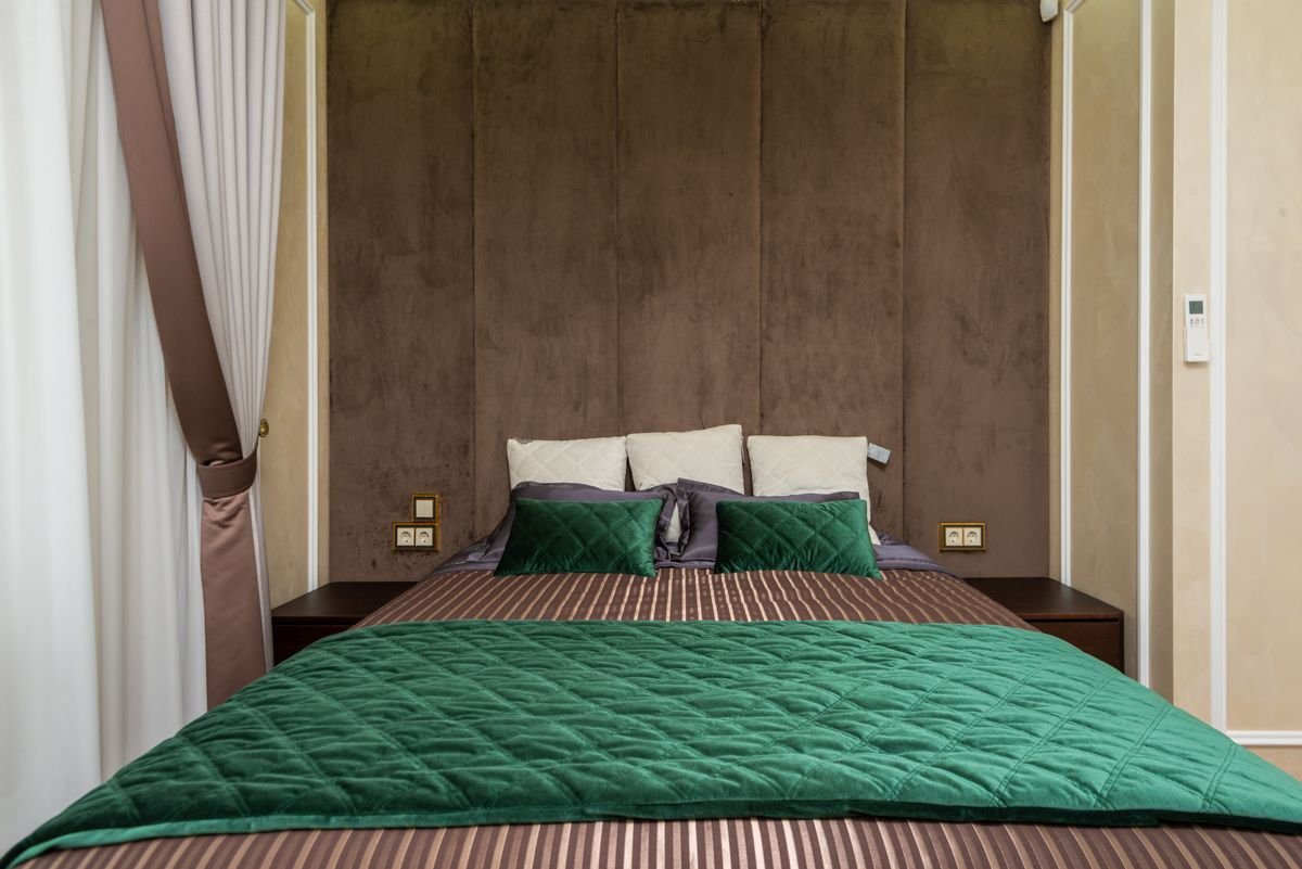 Bed made up with emerald green bedding and white pillows