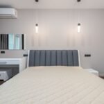 Bedroom with a grey upholstered headboard, white bedding and a built-in desk