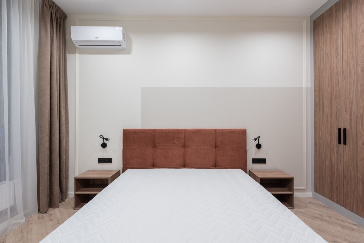 Low-profile bed with a rust-coloured headboard against a wood-panelled wall