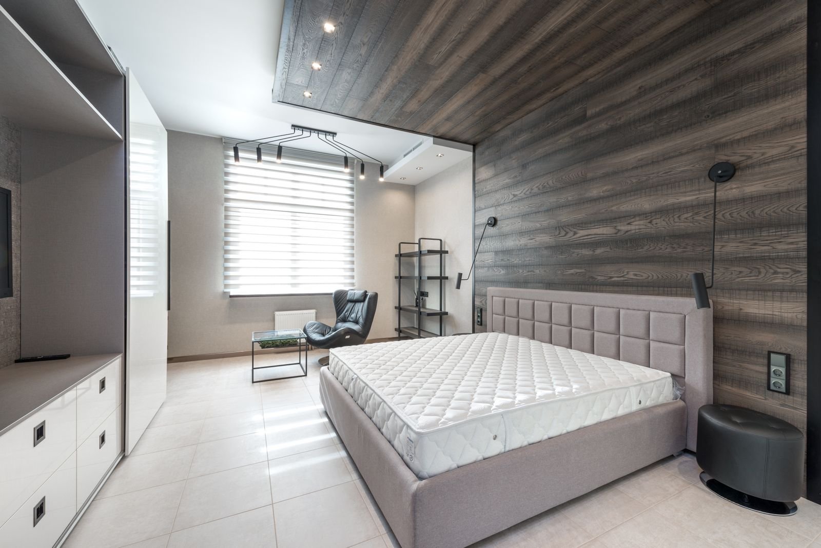 Bare mattress on a bed against a timber feature wall