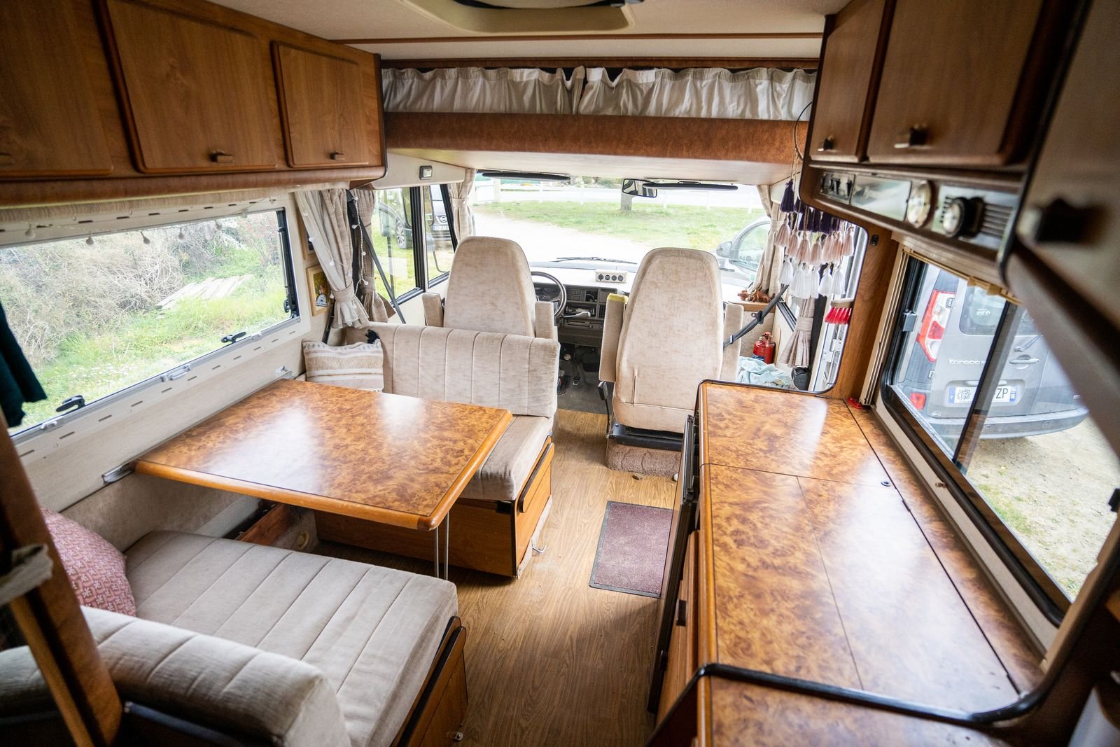 Motorhome interior with a fixed table and bench seating beside large windows