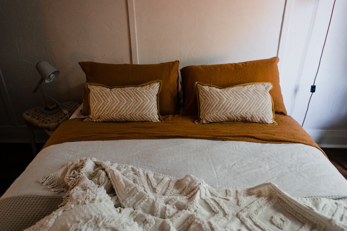 Bed made up with mustard-coloured bedding and matching cushions