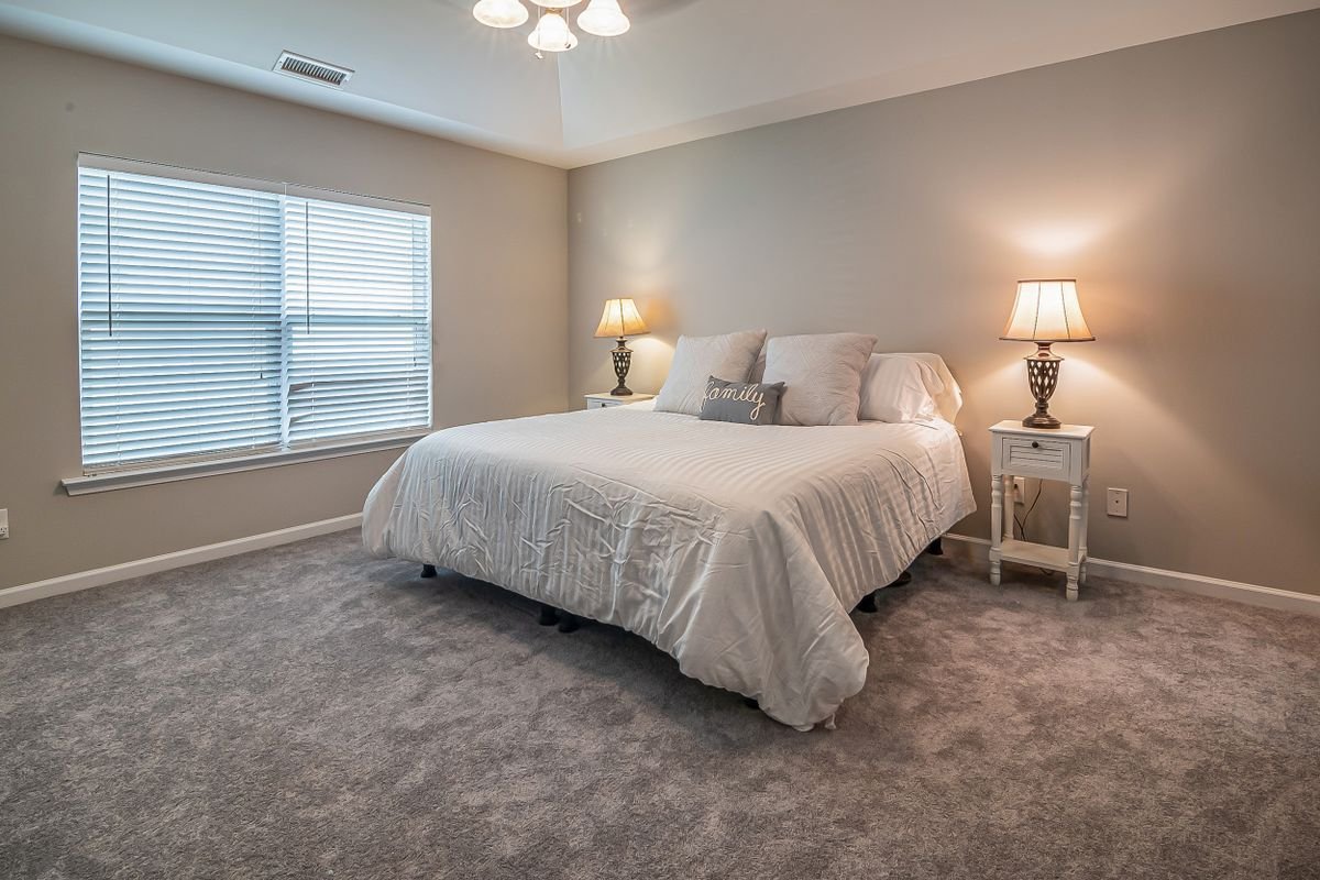Neutral bedroom with a cream bedspread, matching bedside lamps and window blinds