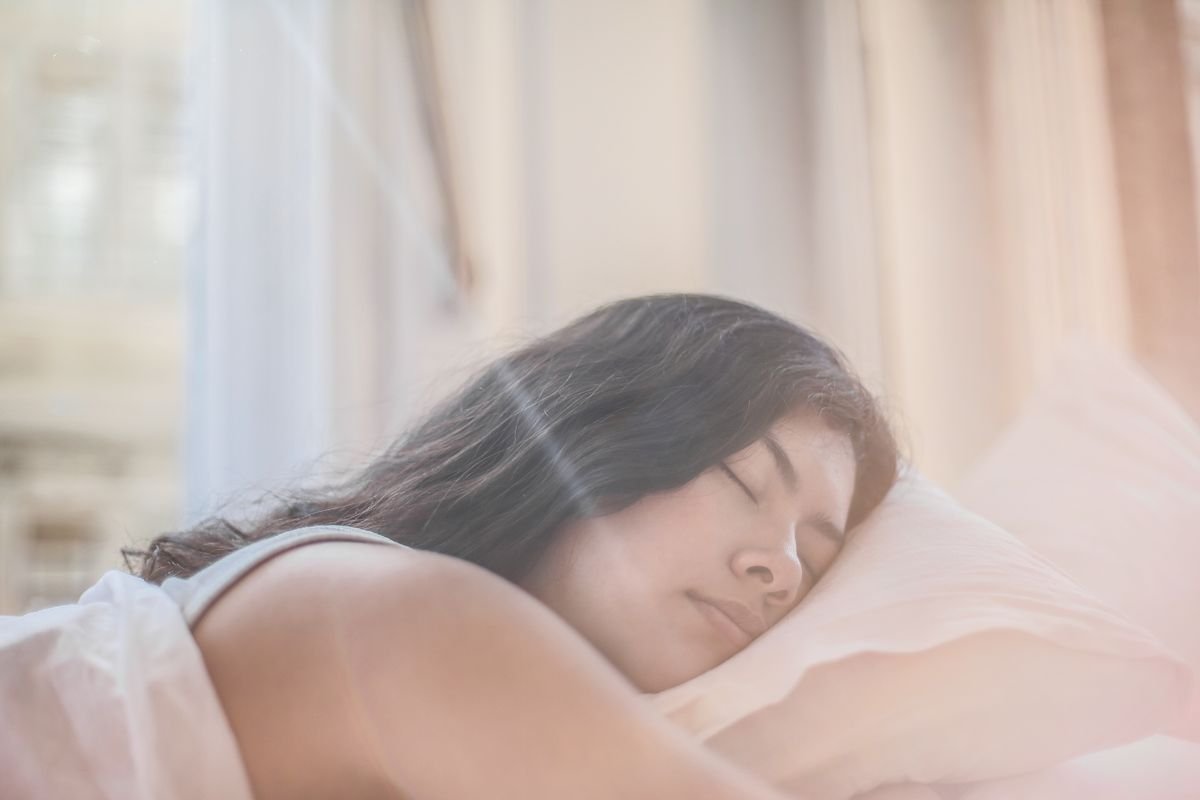 Person sleeping on their side with their face resting on white bedding