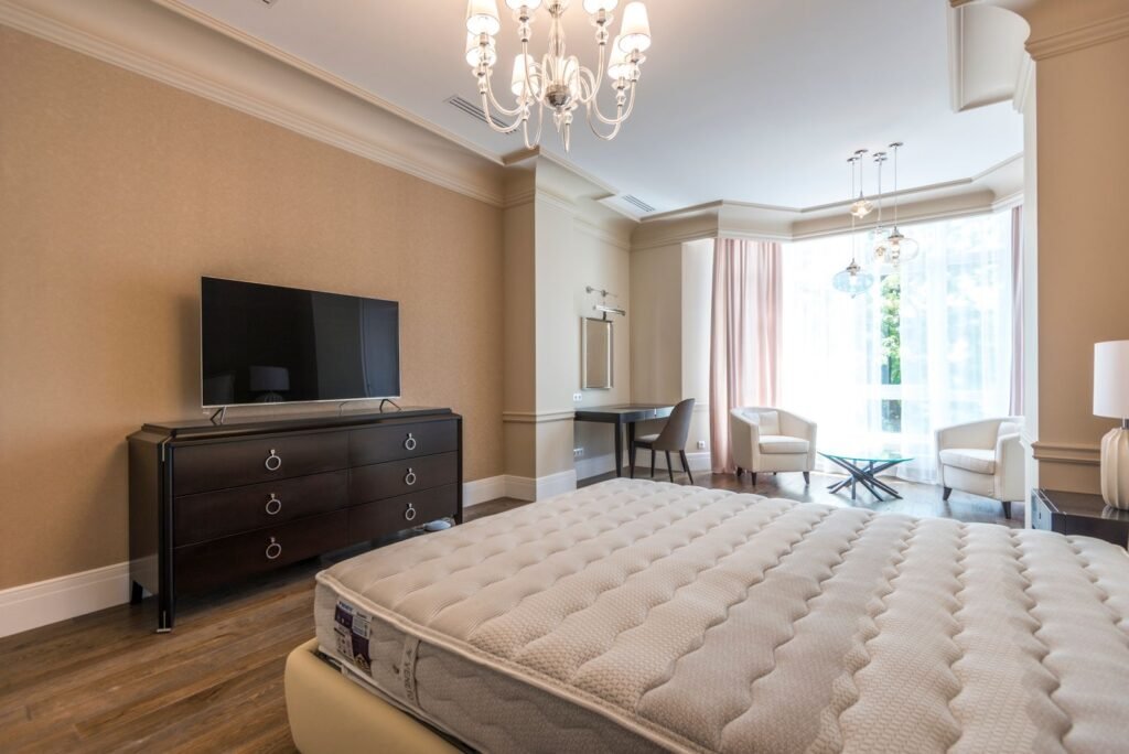 Furnished rental bedroom with a bed, wall-mounted television and a seating area by the window