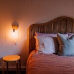Bedroom with a ribbed upholstered headboard, a warm wall light and pink pillows