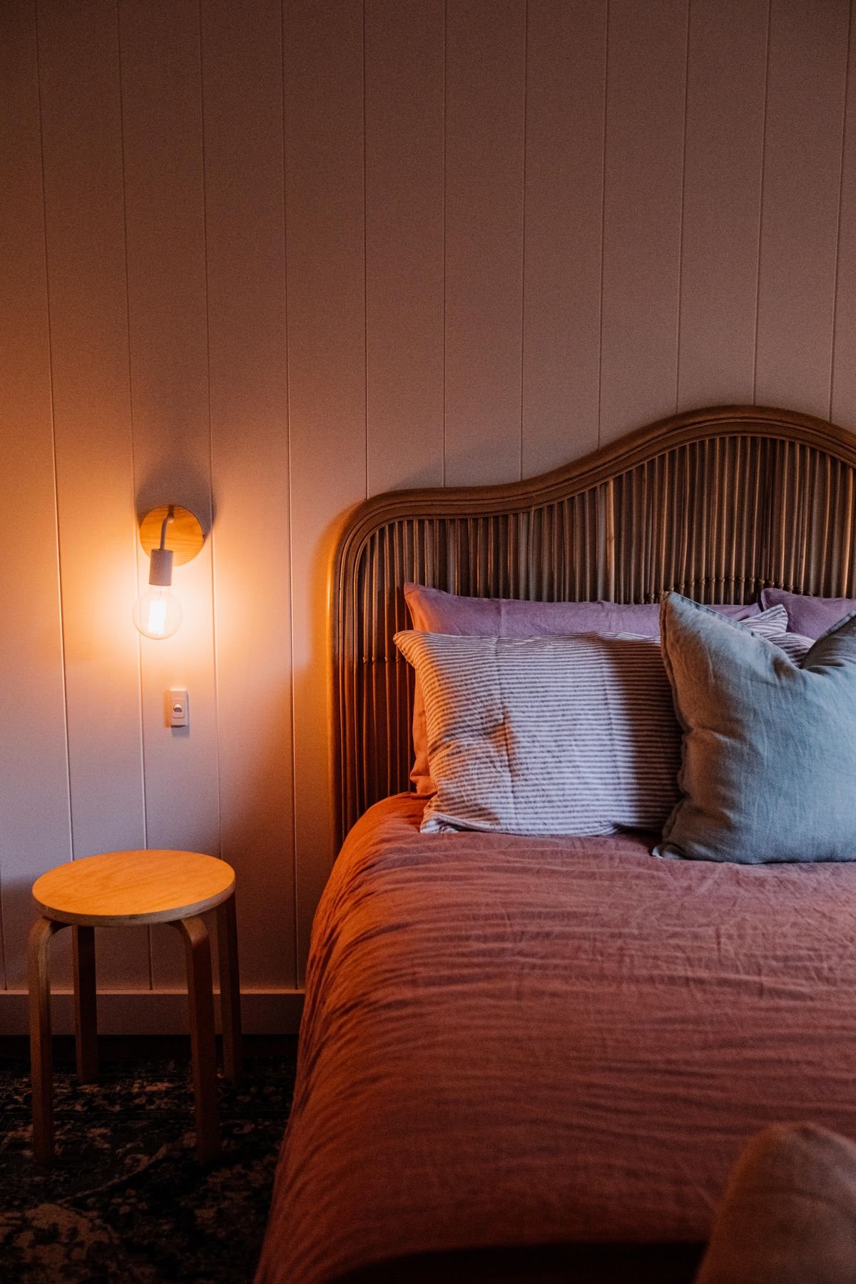 Bedroom with a ribbed upholstered headboard, a warm wall light and pink pillows