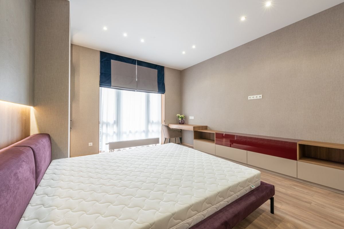 Sparse bedroom with a bare bed base and neutral walls