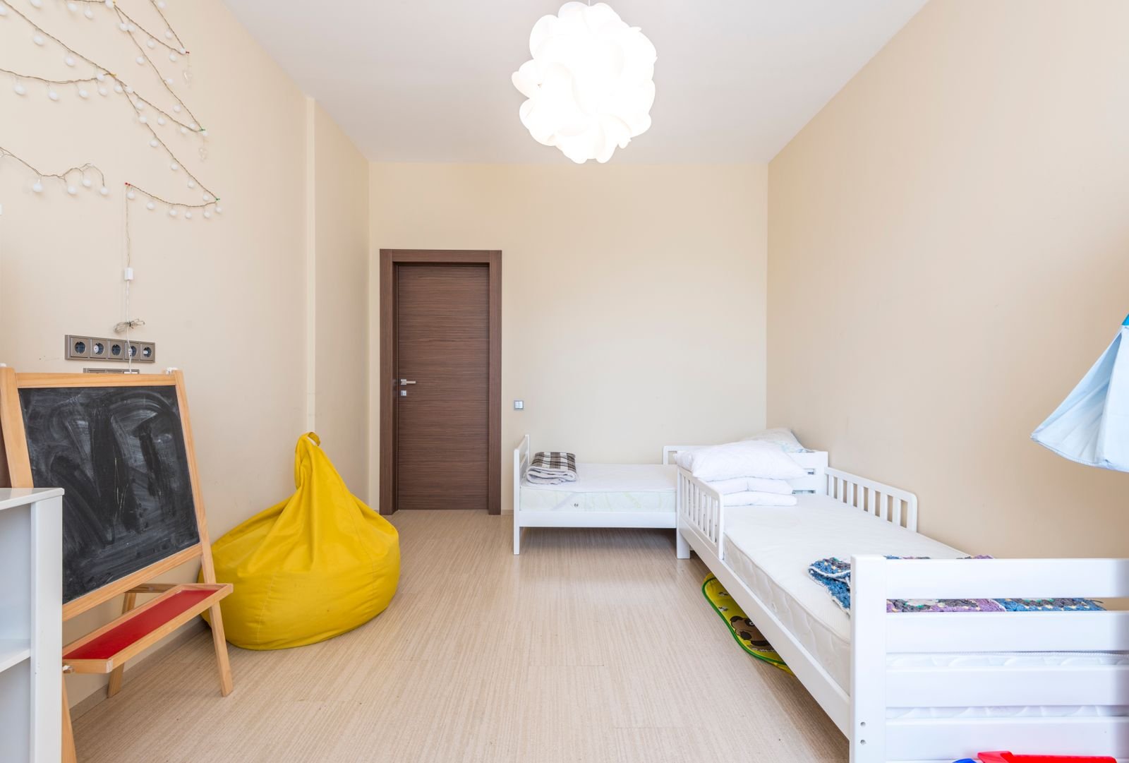 Small white toddler bed with side rails in a child’s room
