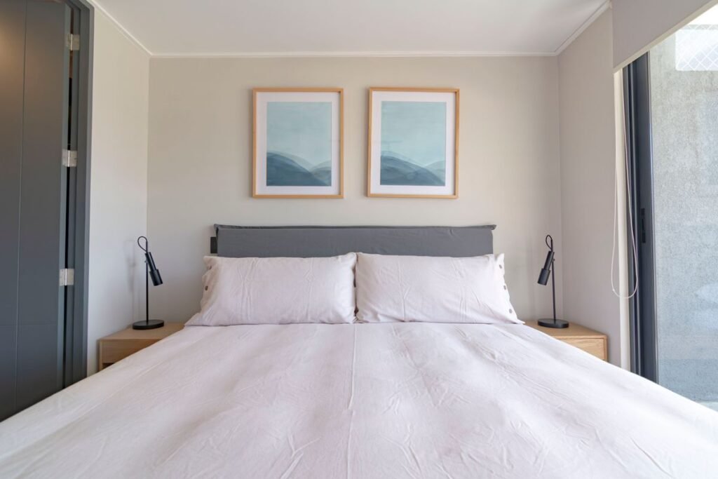 Queen bed with an upholstered headboard and white bedding in a bright bedroom