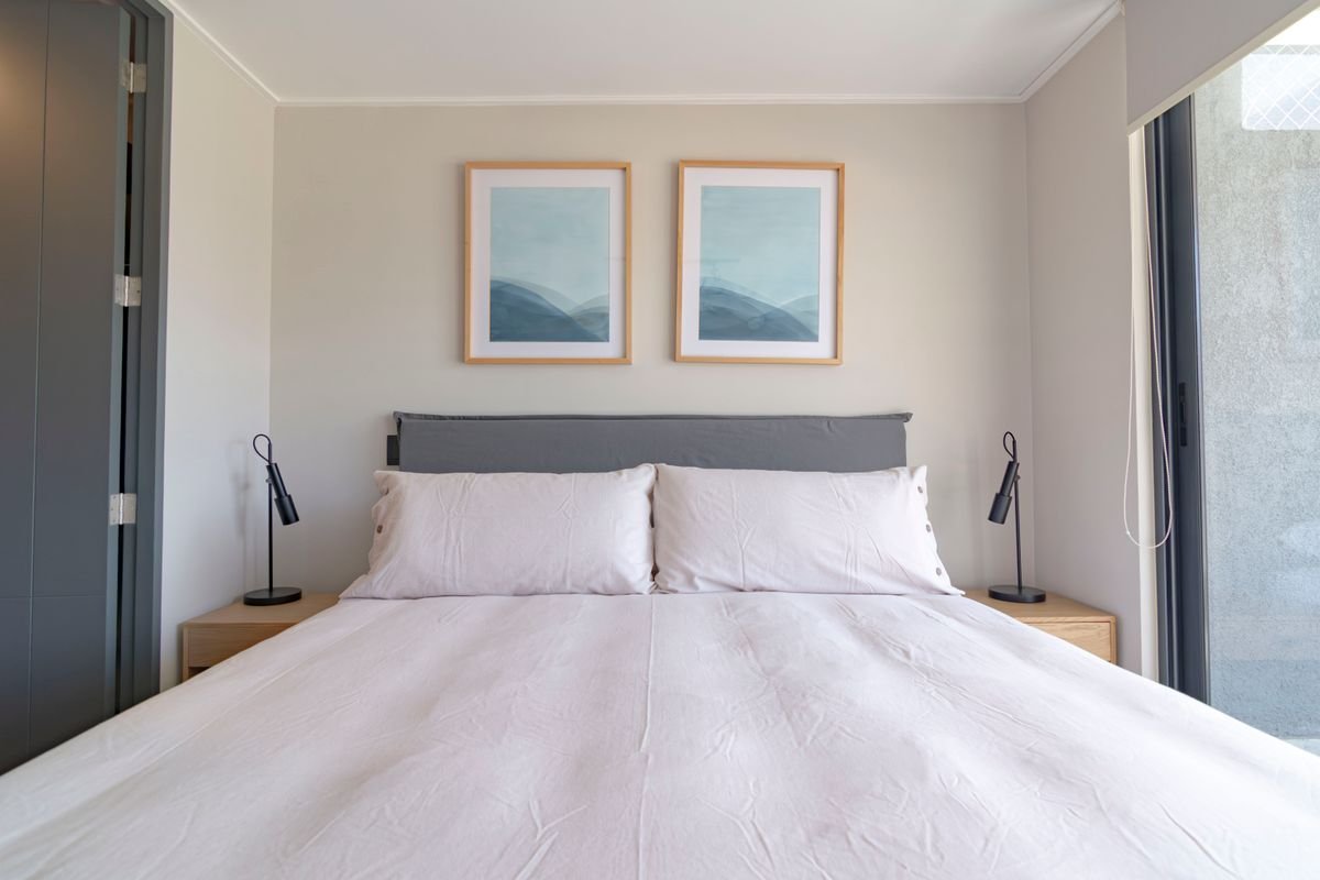 Queen bed with an upholstered headboard and white bedding in a bright bedroom