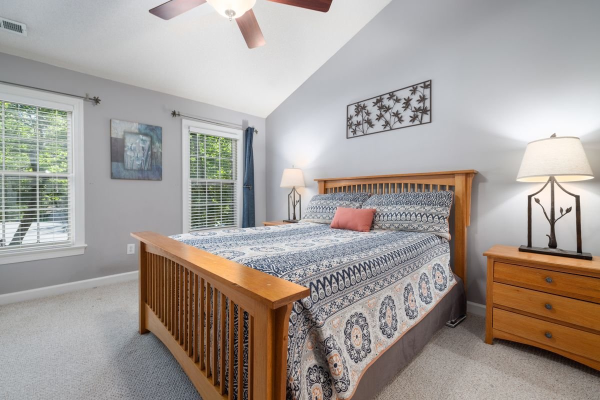 Wooden bed frame with a blue quilt beside a bedroom window