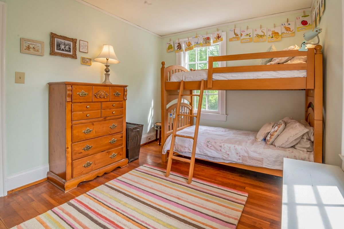 Wooden bunk bed and a matching dresser in a child’s white-walled bedroom